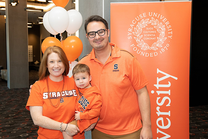 Family poses in front of SU banner